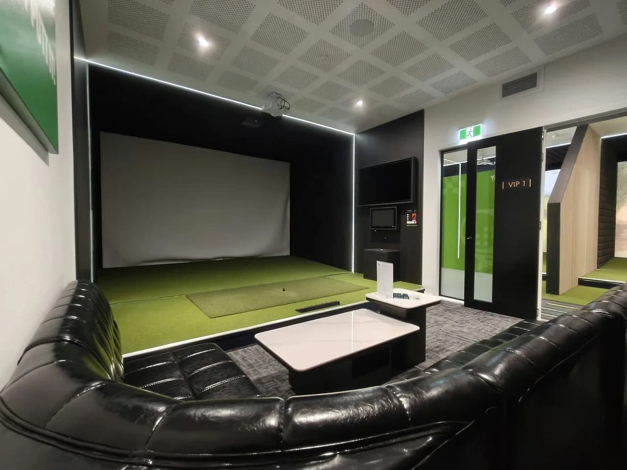 VIP Room 1 at The Tee Bay with a golf simulator, black lounge seating and tables