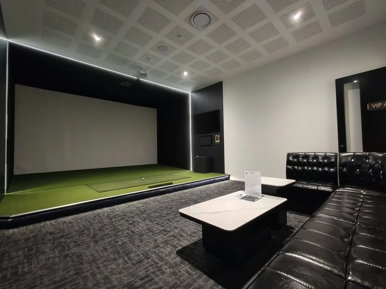 VIP Room 4 at The Tee Bay with a golf simulator, lounge seating and tables